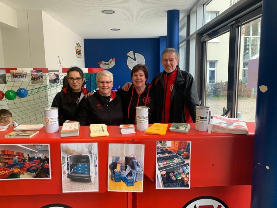 Vier Personen stehen an einem Informationsstand, umgeben von Flyern und Spendenboxen.