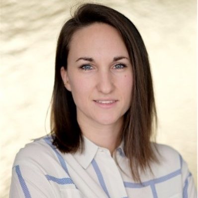 Portrait einer Frau mit mittellangen, braunen Haaren und einem karierten Hemd.