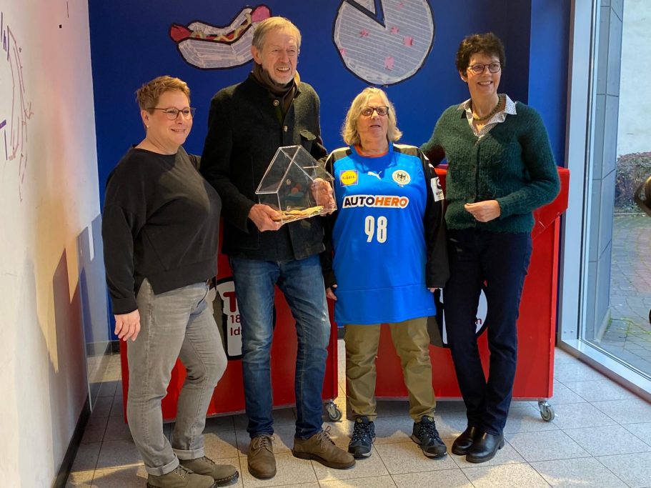 Vier Personen stehen zusammen, präsentieren eine Auszeichnung in einer festlichen Umgebung.